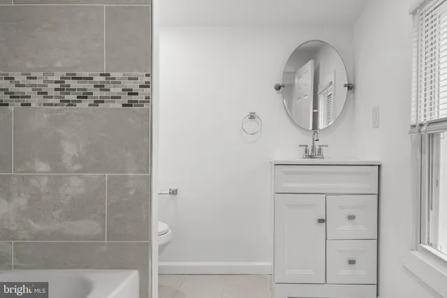a bathroom with a granite countertop sink a mirror and shower