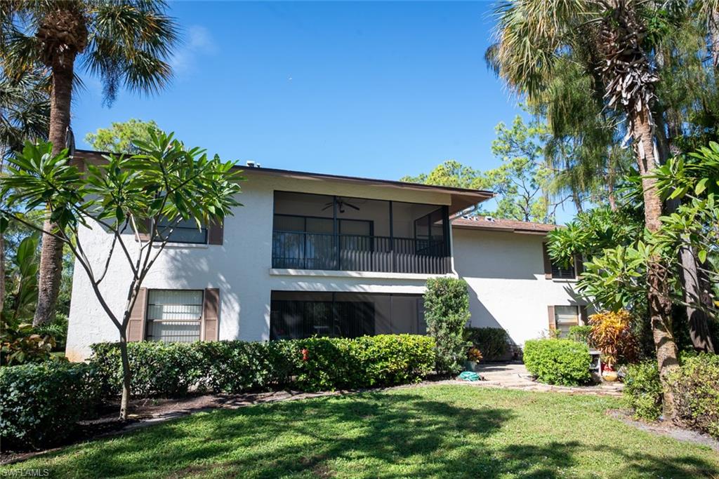 1801 Courtyard Way, Unit D201 Naples, FL 34112 - Photo 35 of 37 a front view of a house with a yard and a garage