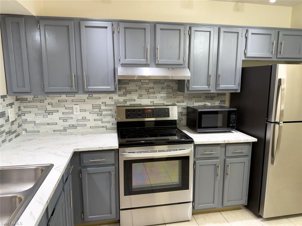 1801 Courtyard Way, Unit D201 Naples, FL 34112 - Photo 4 of 37 a kitchen with a stove top oven cabinetry and refrigerator
