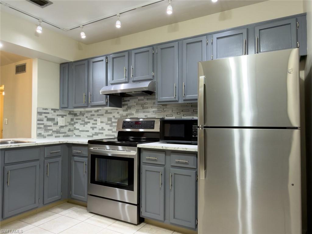 1801 Courtyard Way, Unit D201 Naples, FL 34112 - Photo 5 of 37 a kitchen with stainless steel appliances granite countertop a refrigerator a sink a stove and cabinets