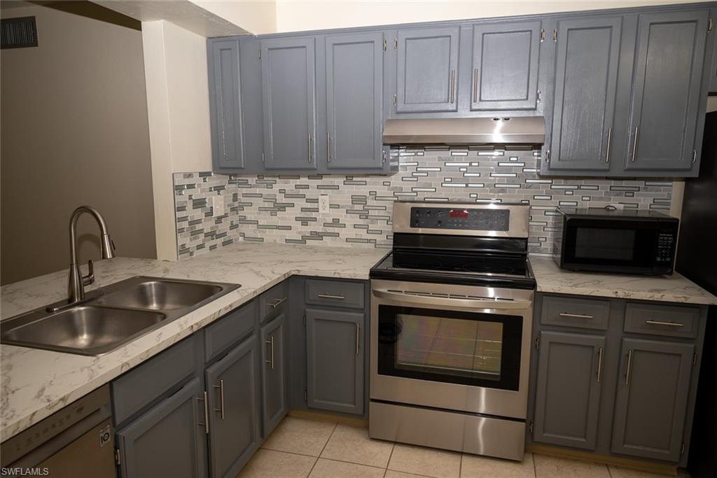 1801 Courtyard Way, Unit D201 Naples, FL 34112 - Photo 7 of 37 a kitchen with granite countertop white cabinets and stainless steel appliances