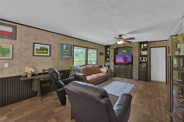 a living room with furniture a flat screen tv and a floor to ceiling window