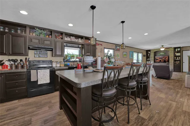 a kitchen with stainless steel appliances kitchen island granite countertop a table chairs in it and wooden floors