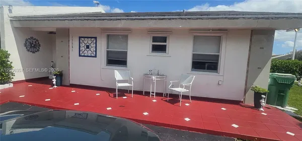 a view of a patio with chairs and table in front of house