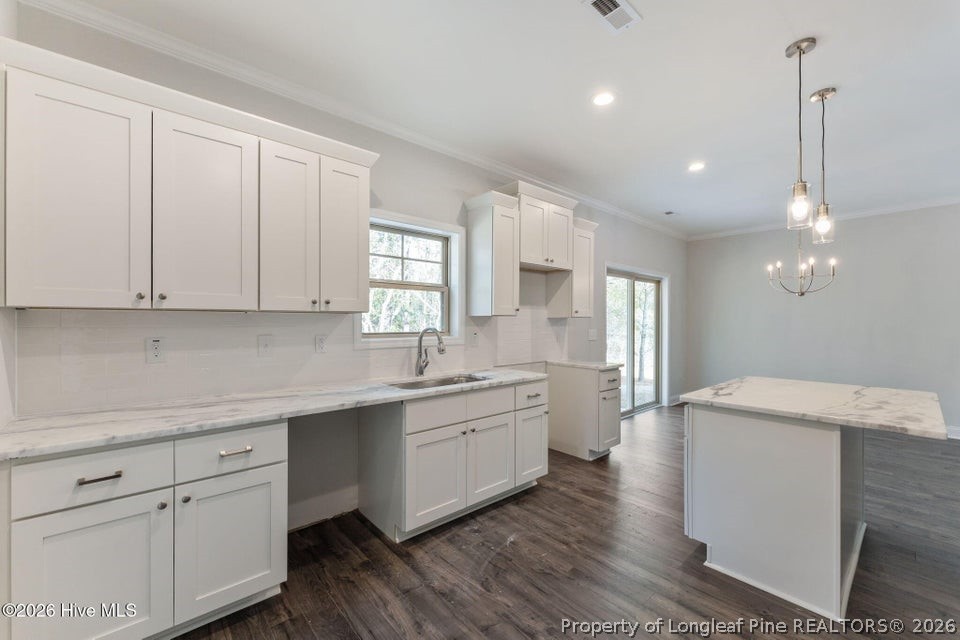229 Telluride Court Aberdeen, NC 28315 - Photo 4 of 19 a kitchen with a sink dishwasher a stove and white cabinets with wooden floor
