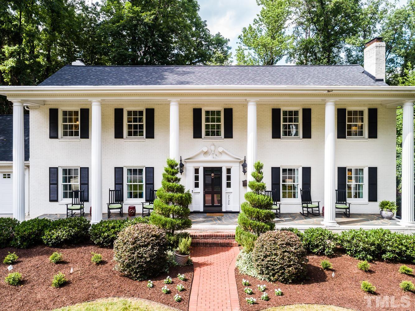 a view of a white house with large windows and plants