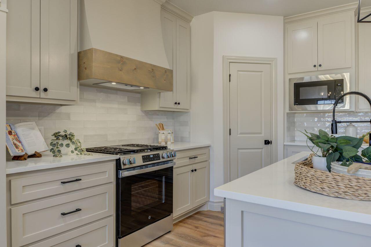 5524 120th Street Lubbock, TX 79424 - Photo 22 of 39 a kitchen with stainless steel appliances white cabinets and a stove top oven