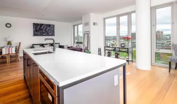 a kitchen with a stove a refrigerator a sink a dining table and chairs with wooden floor