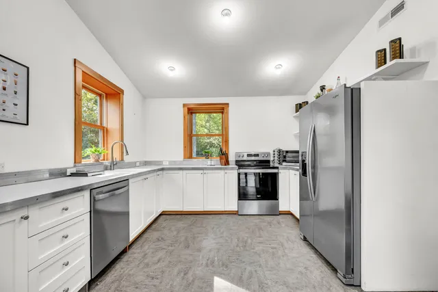 a large white kitchen with a sink and stainless steel appliances