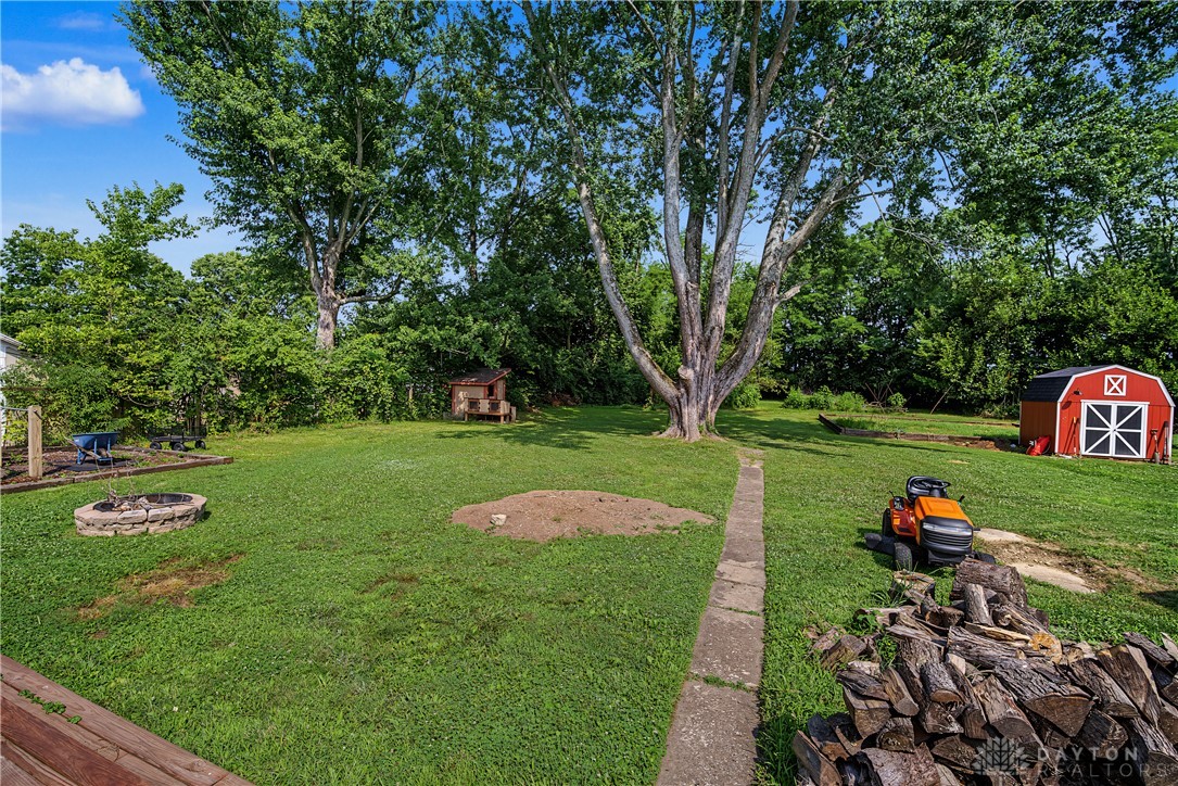 8707 Lytle Ferry Road Waynesville, OH 45068 - Photo 32 of 54 A spacious yard provides ample room for outdoor activities, complemented by mature trees and a charming red shed.