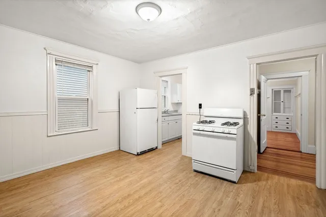 a kitchen with a refrigerator a stove top oven and a wooden floor