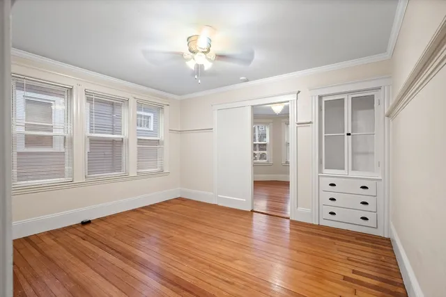 a view of an empty room with wooden floor and cabinet