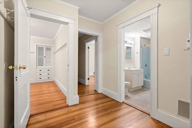 a view of a hallway with wooden floor and a bathroom