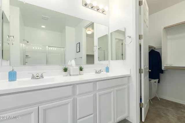 a bathroom with a glass shower door a sink and a mirror