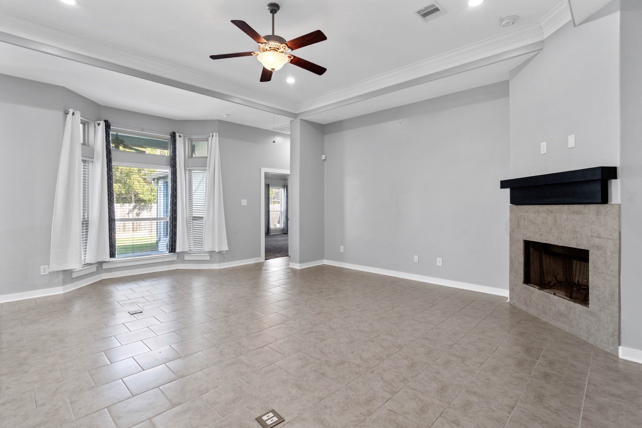 12126 Walden Road Montgomery, TX 77356 - Photo 17 of 50 Spacious and inviting living area featuring a large bay window that brings in abundant natural light and offers beautiful views of the backyard. The open layout provides flexible furniture placement, while the new tile flooring ensures easy maintenance. A modern tiled fireplace with a sleek mantle adds a warm focal point to the room. With high ceilings, LED recessed lighting, and a seamless flow to adjoining spaces, this living room is perfect for both everyday comfort and entertaining.