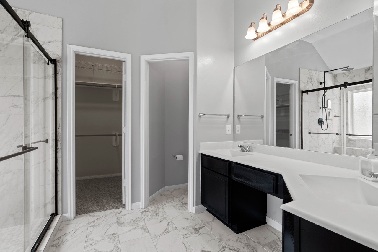 12126 Walden Road Montgomery, TX 77356 - Photo 21 of 50 Beautifully remodeled primary bathroom (2023) featuring elegant marble-look tile flooring, a spacious double vanity with and abundant counter space. Convenient access to the large walk-in closet and a private restroom adds functionality and privacy. Fresh paint, contemporary finishes, and a bright, open layout make this bathroom feel like a luxurious retreat.