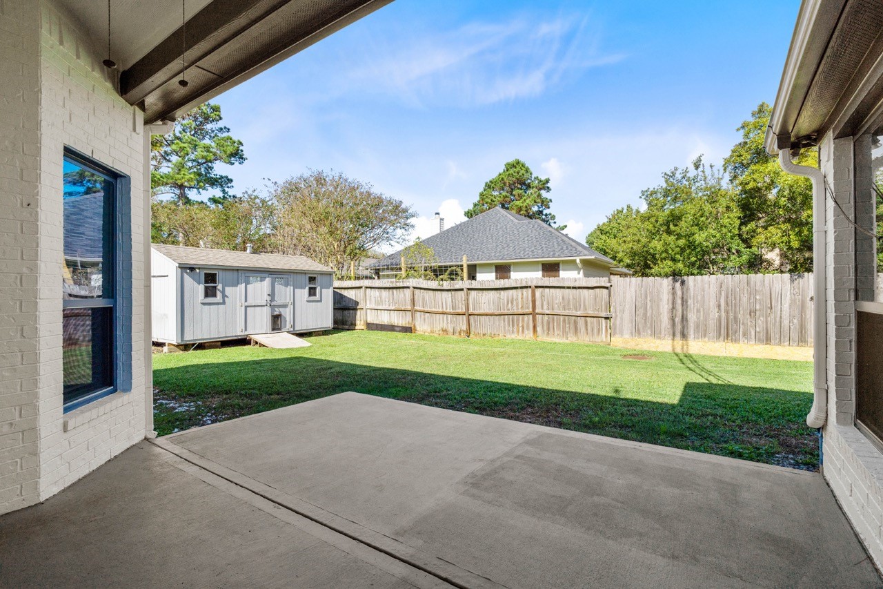 12126 Walden Road Montgomery, TX 77356 - Photo 38 of 50 Enjoy a spacious covered back patio overlooking a large, fully fenced backyard—perfect for outdoor dining, relaxing, or entertaining. The extended concrete pad offers plenty of room for seating, a spa or a grill setup, while the open lawn and shed provide added convenience. A peaceful, private outdoor space ideal for everyday living.