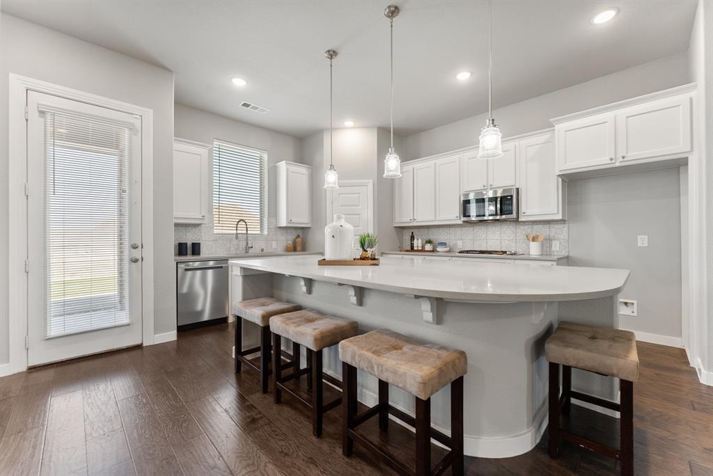 1908 Quail Lane Argyle, TX 76226 - Photo 8 of 30 a kitchen with kitchen island a sink a stove a dining table and chairs