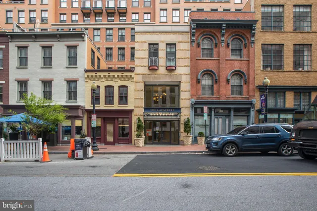 a front view of a building with lot of cars and trees