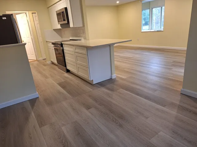 a kitchen with stainless steel appliances cabinets and wooden floor