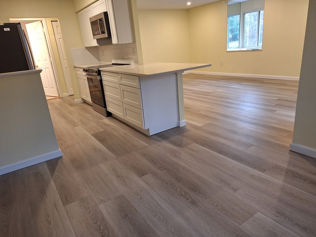 10 Beal's Cove Road, Unit C Hingham, MA 02043 - Photo 2 of 10 a kitchen with stainless steel appliances cabinets and wooden floor