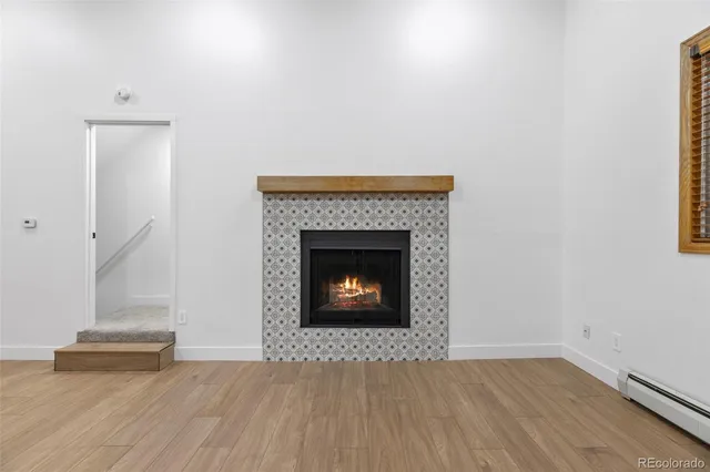 a view of an empty room with wooden floor and a fireplace