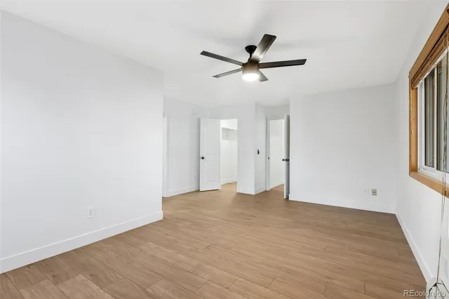 an empty room with wooden floor closet and windows