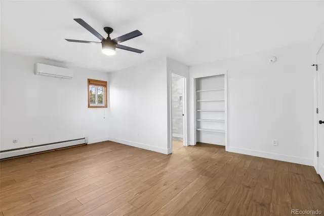 an empty room with wooden floor fan and windows