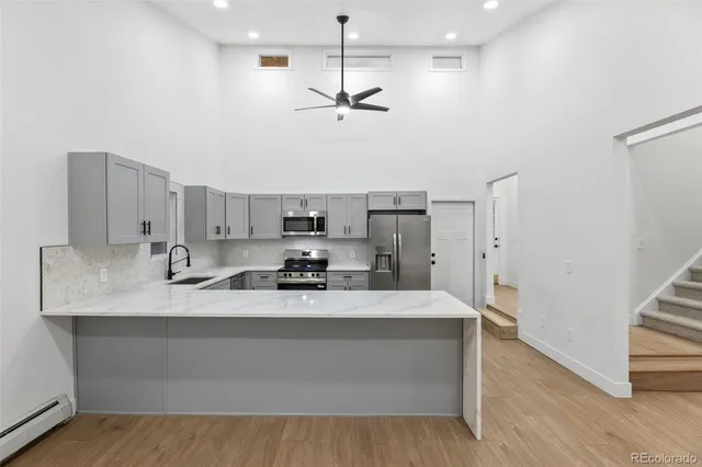 a large white kitchen with kitchen island stainless steel appliances a stove a sink and a refrigerator