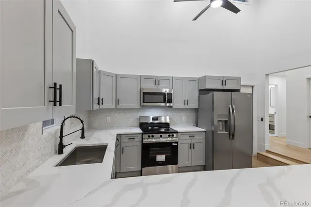 a kitchen with granite countertop a refrigerator and a stove top oven