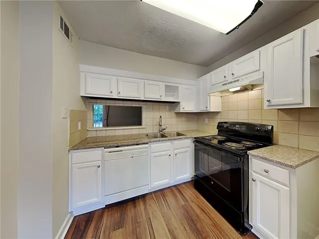 a kitchen with stainless steel appliances granite countertop a stove a sink and white cabinets