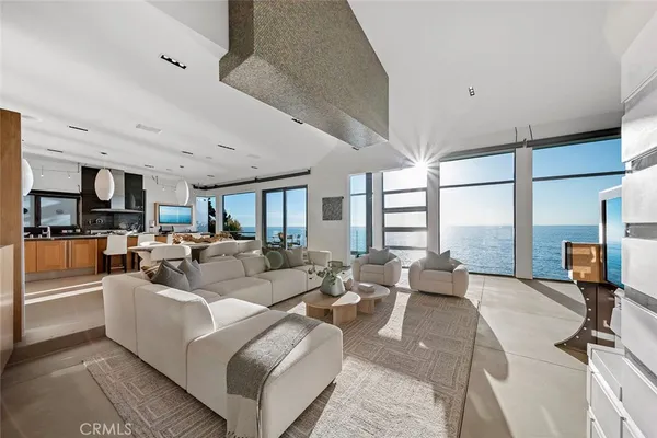 a living room with furniture large windows and kitchen view