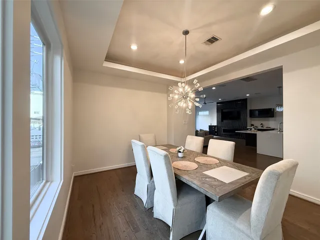 a dining room with furniture a chandelier and wooden floor