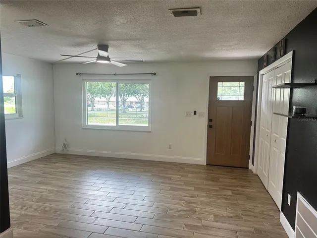 an empty room with wooden floor a ceiling fan and windows
