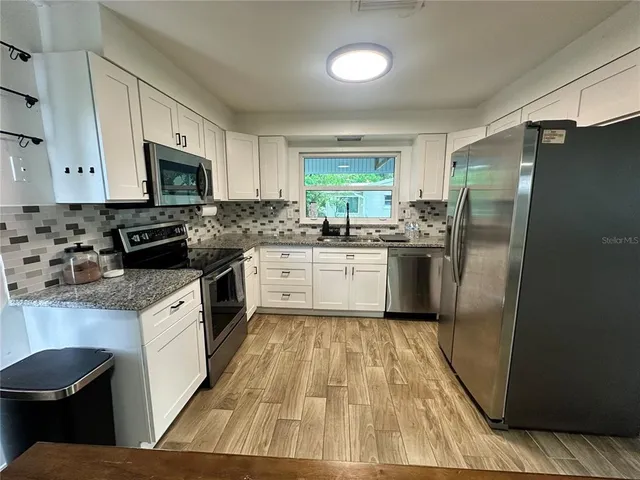 a kitchen with a sink white cabinets and stainless steel appliances