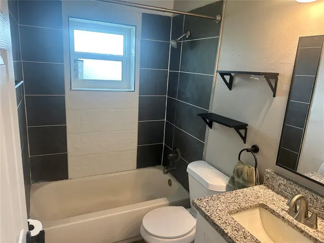 a bathroom with a granite countertop bathtub sink vanity mirror and toilet