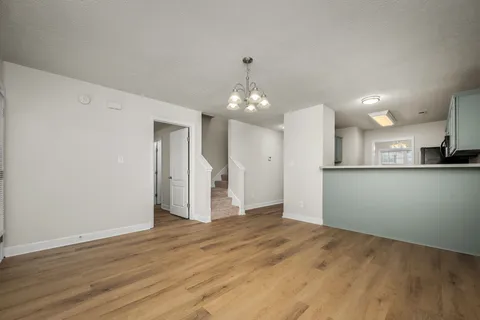 a view of an empty room with kitchen and a window