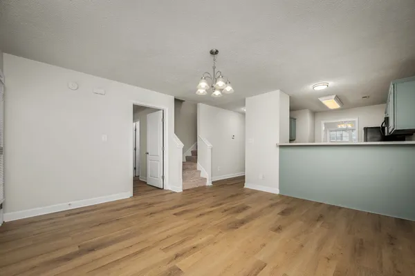 a view of an empty room with kitchen and a window