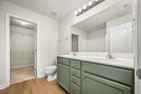 a spacious bathroom with a granite countertop sink a toilet and a mirror