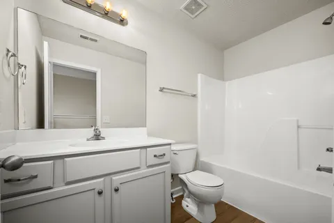 a bathroom with a sink a toilet a mirror and shower