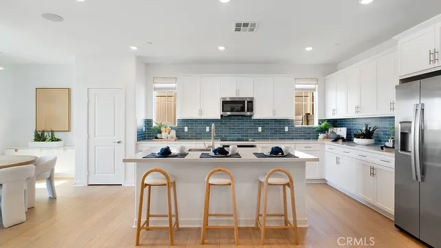 a kitchen with stainless steel appliances granite countertop a stove a sink a refrigerator a dining table and chairs