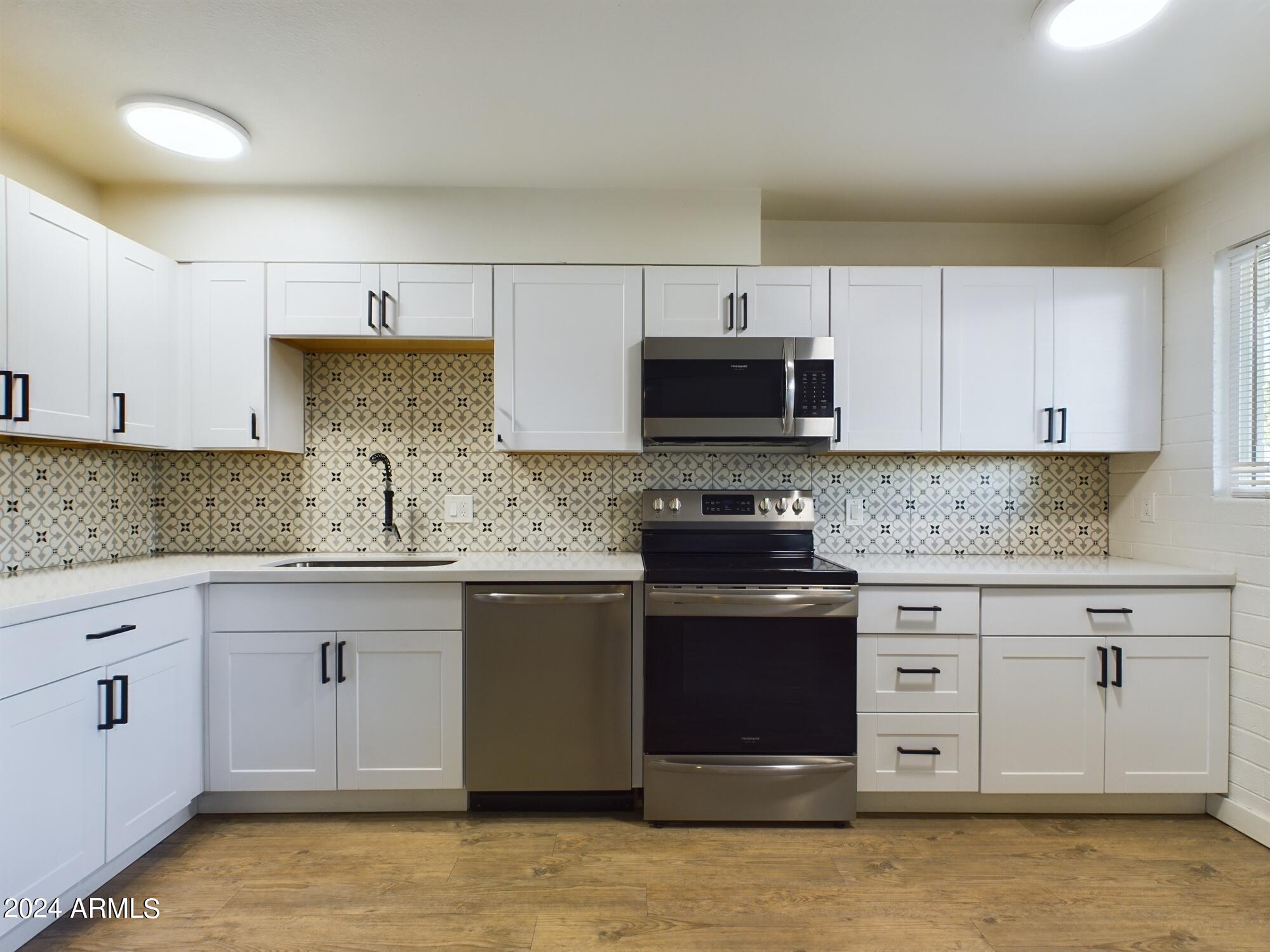 3027 North 37th Street, Unit 3 Phoenix, AZ 85018 - Photo 3 of 12 a kitchen with stainless steel appliances granite countertop a stove a sink and a microwave