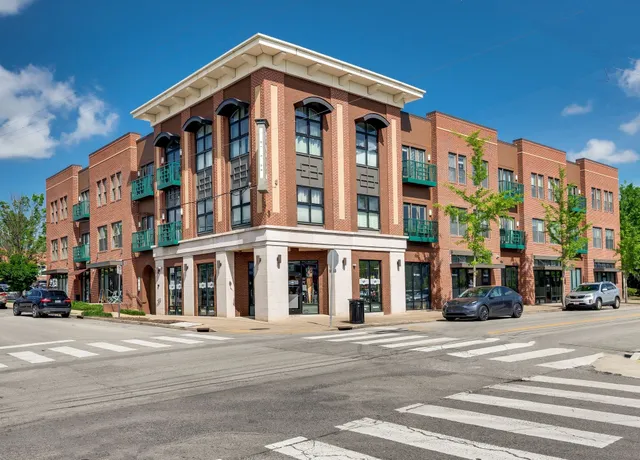 a front view of multi story residential apartment building with parked cars