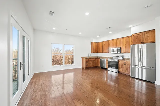 a view of kitchen with stainless steel appliances a refrigerator and wooden floor
