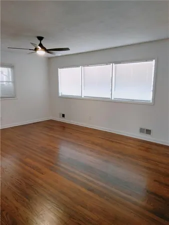 a view of an empty room with wooden floor and a window