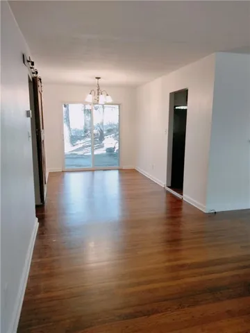 a view of a living room with wooden floor and kitchen view