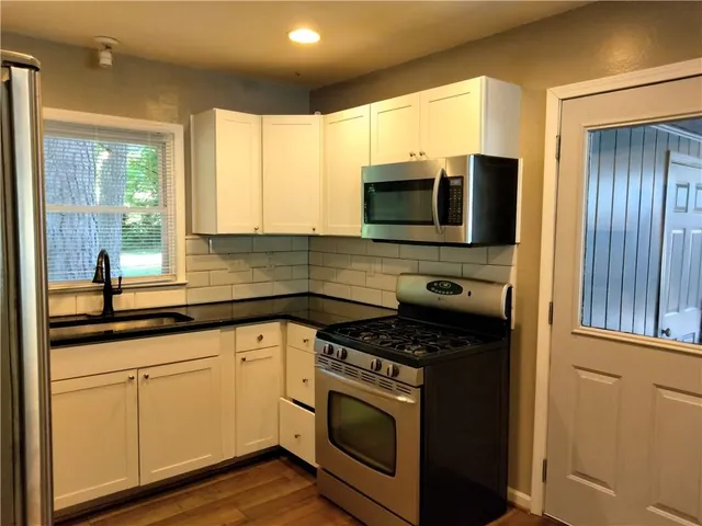 a kitchen with stainless steel appliances granite countertop white cabinets granite counter tops and a window
