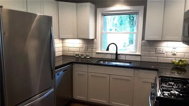 a kitchen with granite countertop a refrigerator sink and cabinets