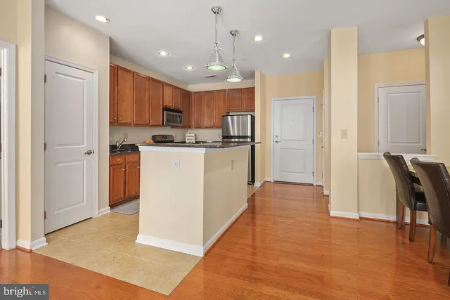 a kitchen with stainless steel appliances granite countertop a refrigerator a stove top oven a sink dishwasher and a refrigerator with wooden floor