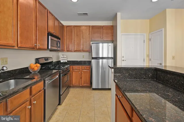 a kitchen with granite countertop a sink a stove and refrigerator